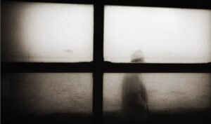 atmospheric black and white silouete of a man through a window with interesting light